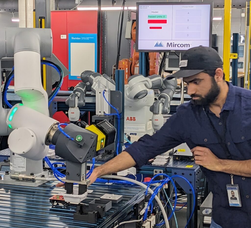 Sheridan's CIM team member works with the robotic assembly and testing cell developed for Mircom’s fire prevention controllers.